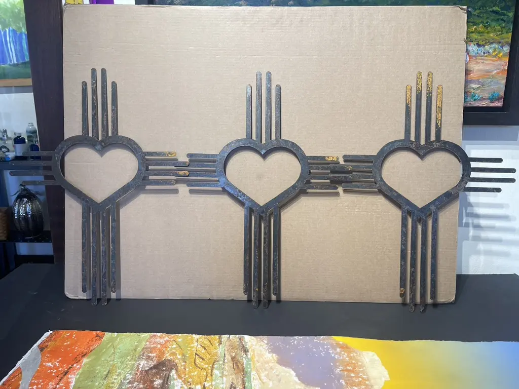 Three heart shaped metal sculptures on top of a cardboard box.