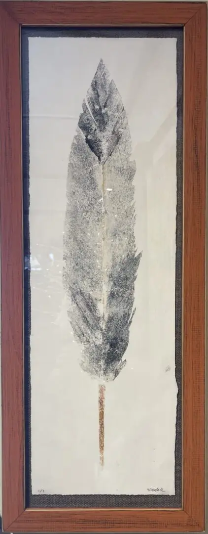 A framed print of a leaf on a wall.